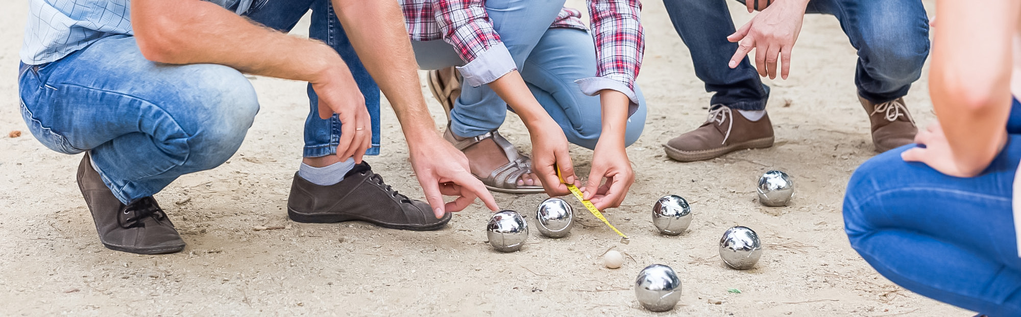 Personnes jouant à la pétanque mesurent la distance.