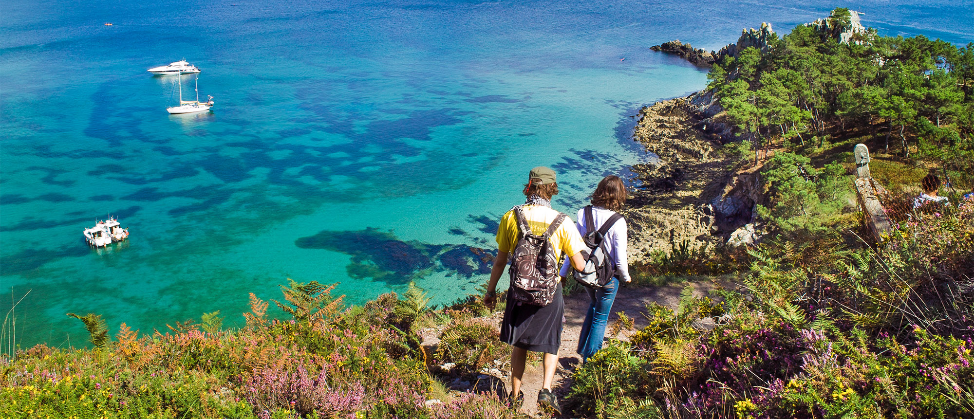 Randonneurs admirant la mer turquoise bretonne.
